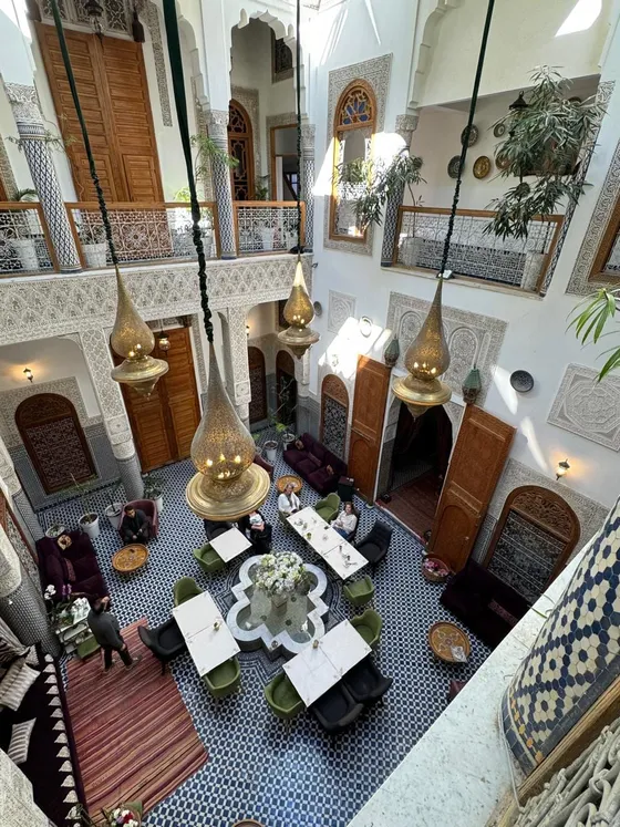 Pátio interno de um riad em Marraquexe com lustres de latão e azulejos, Marrocos